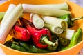 Leek, green pepper and red pepper in yellow bowl.