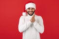 Leery hipster man wears santa claus hat over red background. Christmas and New Year concept.