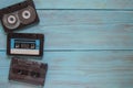 In the left corner of the frame, on a blue wooden background, there are three audio cassettes. On the right, there is an empty