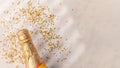 In the left corner of the photo we see a bottle of champagne with a golden neck. Lots of golden confetti are scattered around. Royalty Free Stock Photo
