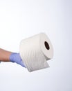 Left hand in blue glove holding a roll of toilet paper Royalty Free Stock Photo