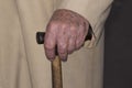 Hand of an elderly woman holding a wooden crutch.