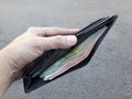 Left hand holding black leather wallet with full of money Royalty Free Stock Photo