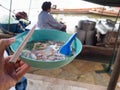 Left hand holding a bowl of noodles. The river is behind and there are noodle boats. thailand lifestyle