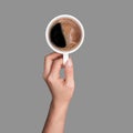 Left hand holding cup of coffee on grey background Royalty Free Stock Photo
