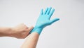 Left hand is pulling right hand with blue latex gloves on white background Royalty Free Stock Photo