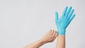 Left hand is pulling right hand with blue latex gloves on white background Royalty Free Stock Photo