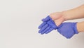 Left hand is pulling right hand with purple latex gloves on white background Royalty Free Stock Photo