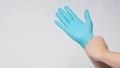 Left hand is pulling right hand wearing blue latex gloves on white background Royalty Free Stock Photo