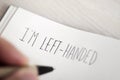 Left-handed man writing the text I am left-handed Royalty Free Stock Photo