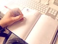 Left-handed person writing on the blank pages of a diary using a red pen Royalty Free Stock Photo