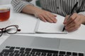 Left-handed woman writing in notebook at table indoors, closeup Royalty Free Stock Photo