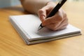 Left-handed woman writing in notebook at wooden desk, closeup Royalty Free Stock Photo