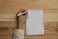 Left-handed woman writing in notebook at wooden table, top view Royalty Free Stock Photo