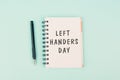 Left handers day is standing on a notebook, writing with the left hand, pen and table Royalty Free Stock Photo