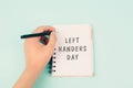 Left handers day is standing on a notebook, writing with the left hand, pen and table Royalty Free Stock Photo
