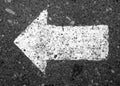 Left pointing arrow on asphalt in black and white