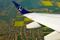 left wing of commercial passenger airplane of Polish LOT carrier. agricultural field below.