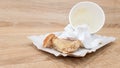 Leftover food on a paper plate and empty dirty paper coffee cup on a wooden table in a fast food cafe Royalty Free Stock Photo