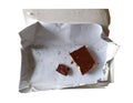 Leftover food, pieces of chocolate in the package. Junkfood on a diet. Cocoa tile isolated on white