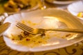 Leftovers and fork on white plate. Dirty empty plate with fork on a table in restaurant after dinner. Royalty Free Stock Photo