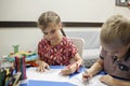 Lefty girl and righty boy writing at same desk and nudge each other with elbows, left-hander day