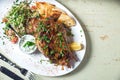 Leg of lamb baked with sauce in the white plate closeup with a side dish of rice. Rustic wooden table and a glass of red Royalty Free Stock Photo