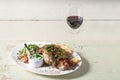 Leg of lamb baked with sauce in the white plate closeup with a side dish of rice. Rustic wooden table and a glass of red Royalty Free Stock Photo