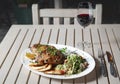 Leg of lamb baked with sauce in the white plate closeup with a side dish of rice. Rustic wooden table and a glass of red wine. Royalty Free Stock Photo