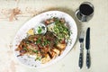 Leg of lamb baked with sauce in the white plate closeup with a side dish of rice. Rustic wooden table and a glass of red Royalty Free Stock Photo