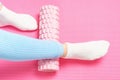 Leg rolls a massage foam roller close-up on pink background, top view. Royalty Free Stock Photo