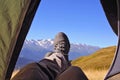 Leg tourist in boots out of the tent with mountains Royalty Free Stock Photo