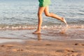 Leg of woman running on beach with water splashing. summer vacation. legs of a girl walking in water on sunset Royalty Free Stock Photo