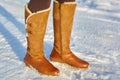 Leg woman winter brown fur boots walking on the snow in a winter park. Closeup outsole of warm boot. Royalty Free Stock Photo