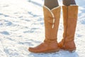 Leg woman winter brown fur boots walking on the snow in a winter park. Closeup outsole of warm boot. Royalty Free Stock Photo