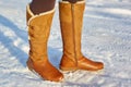 Leg woman winter brown fur boots walking on the snow in a winter park. Closeup outsole of warm boot. Royalty Free Stock Photo