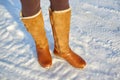 Leg woman winter brown fur boots walking on the snow in a winter park. Closeup outsole of warm boot. Royalty Free Stock Photo