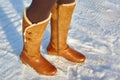 Leg woman winter brown fur boots walking on the snow in a winter park. Closeup outsole of warm boot. Royalty Free Stock Photo