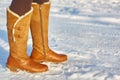 Leg woman winter brown fur boots walking on the snow in a winter park. Closeup outsole of warm boot. Royalty Free Stock Photo