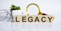 LEGACY concept on wooden cubes and flower ,glasses ,coins and magnifier on the white background Royalty Free Stock Photo