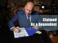 Legal concept about Claimed As a Dependent Male office workers with yellow shirt holding and writing documents on office desk