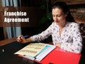 Legal concept about Franchise Agreement Female office workers with yellow shirt holding and writing documents on office desk