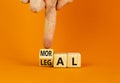 Legal or moral symbol. Businessman turns wooden cubes and changes the word Legal to Moral on a beautiful orange table orange Royalty Free Stock Photo