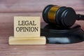 Legal opinion text engraved on wooden block with gavel background. Legal and law concept