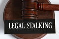 LEGAL STALKING - words on a black sheet against the background of a judge\'s gavel