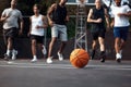 Legends playing together. Closeup shot of a basketball on a sports court with a group of young men in the background. Royalty Free Stock Photo