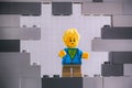 Lego Boy minifigure looking through a hole in gray wall