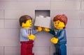 Lego businessman and businesswoman with gray brick ready to finishing building wall