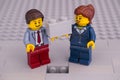 Lego businessman and businesswoman minifigures with brick ready to finishing gray building wall Royalty Free Stock Photo