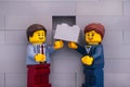 Lego businessman and businesswoman minifigures with gray brick ready to finishing building wall Royalty Free Stock Photo